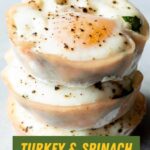 Three spinach egg cups stacked atop one another on a light background. A text overlay reads, "Turkey & Spinach Egg Cups."