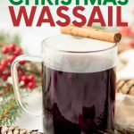 A mug of Christmas wassail sits with a cinnamon stick balanced across the rim. A text overlay reads, "Secret Family Recipe! Christmas Wassail."